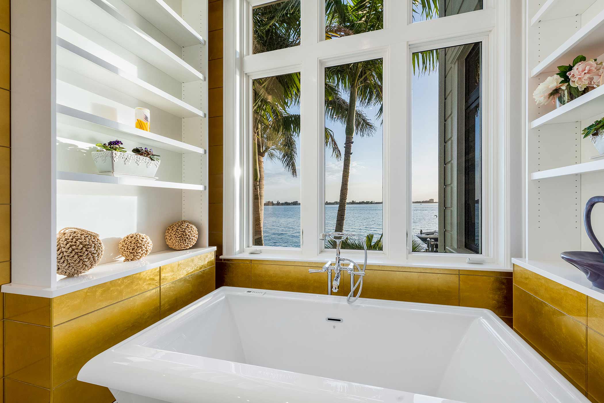 Custom bathroom design with gold tile and a white soaking tub in Sarasota, Florida